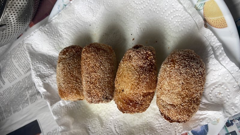 Bread rolls — four oval, deep-fried rolls coated in granulated sugar, resting on paper towels.