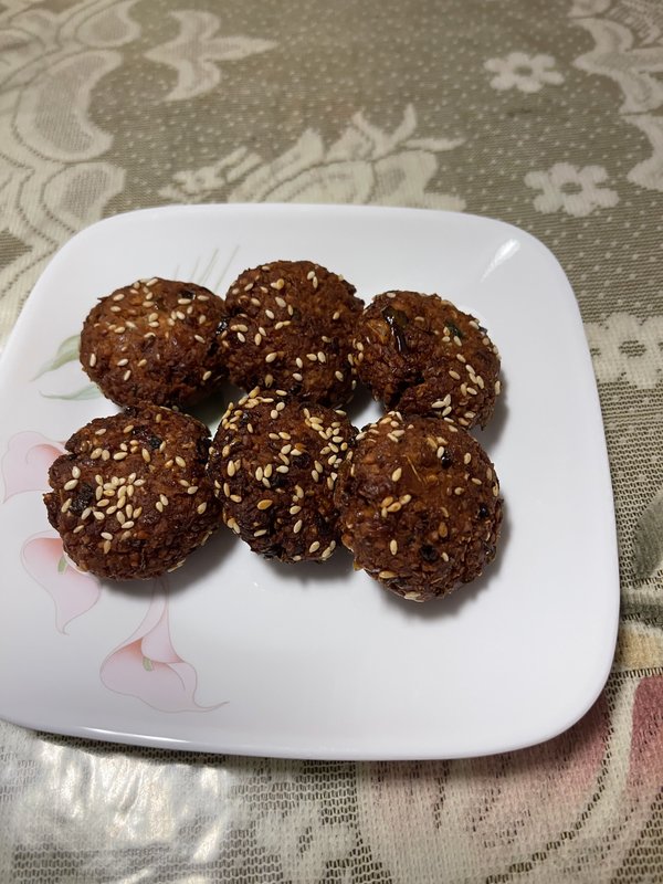 Falafel: roughly 25 round, dark brown fried chickpea balls arranged in a rectangular aluminum foil tray, with no garnishes or accompaniments visible.
