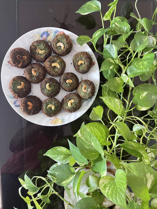 Hara Bhara Kebab: round, green patties coated in breadcrumbs, each topped with a cashew half, arranged on a white plate.