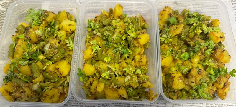 **Long Beans Stir Fry:** Three plastic containers filled with stir-fried long beans and potato chunks, seasoned with spices and garnished with fresh chopped cilantro.
