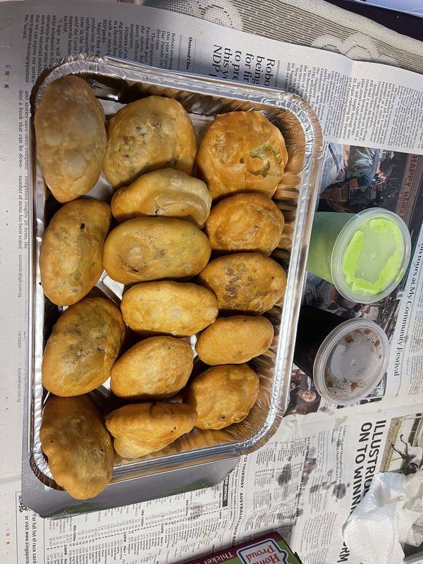 Kachori — a tray of round, deep-fried pastry shells filled with spiced lentil, onion, or pea filling, served with green chutney and tamarind sauce on the side.