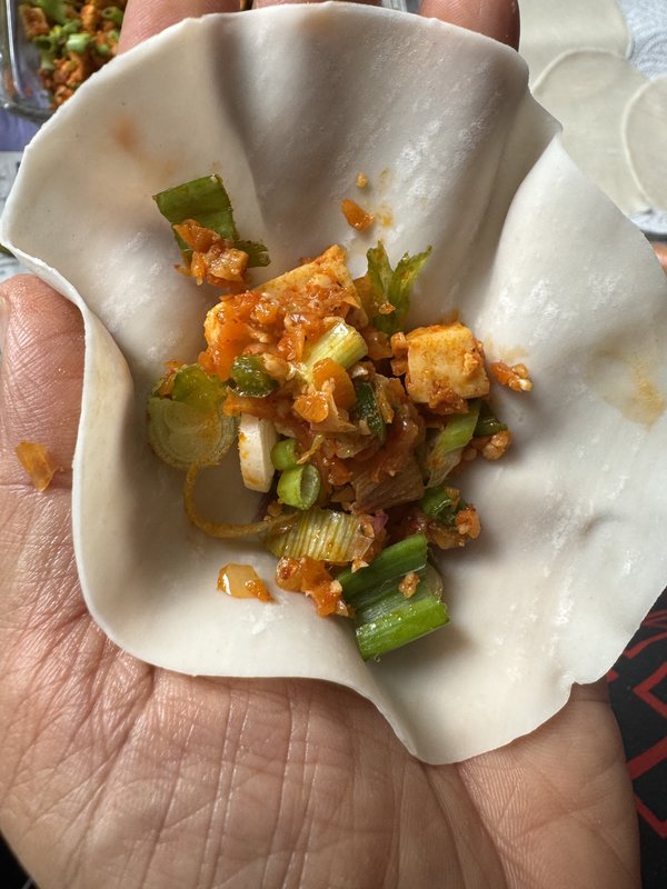**Paneer Momos** — a glass baking dish filled with spiced, crumbled paneer coated in orange-red masala, mixed with chopped green onions and celery pieces.