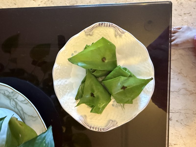 **Paan:** Several folded betel leaves, each secured with a clove, arranged on a white decorative plate.