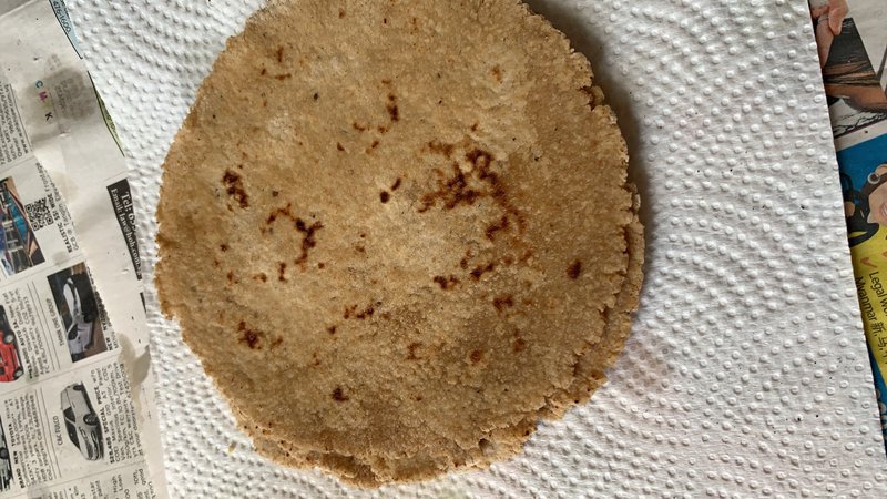 Oats paratha: a round, flat whole-grain flatbread with brown toasted spots, resting on a paper towel.