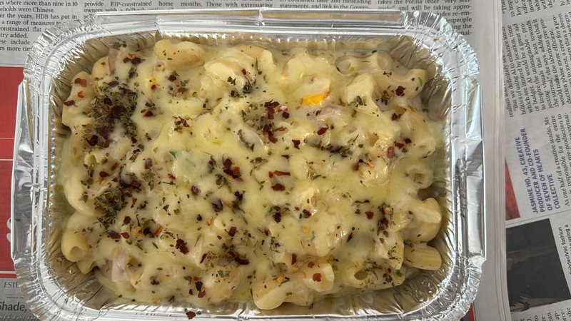 White Pasta (Small): baked macaroni in white cheese sauce, topped with melted cheese, dried herbs, and red chilli flakes, served in a foil tray.